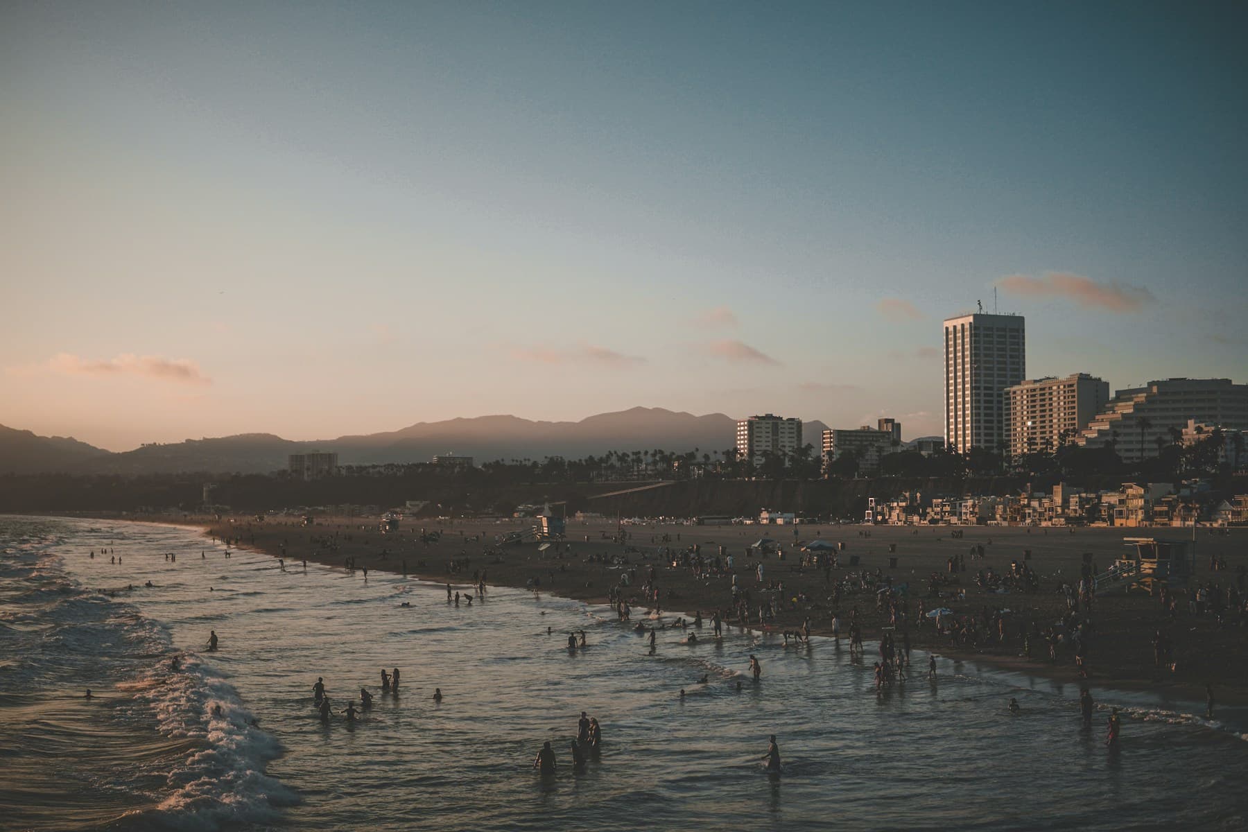 View from Santa Monica Pier looking back toward the beach, shoreline, and city at sunset
