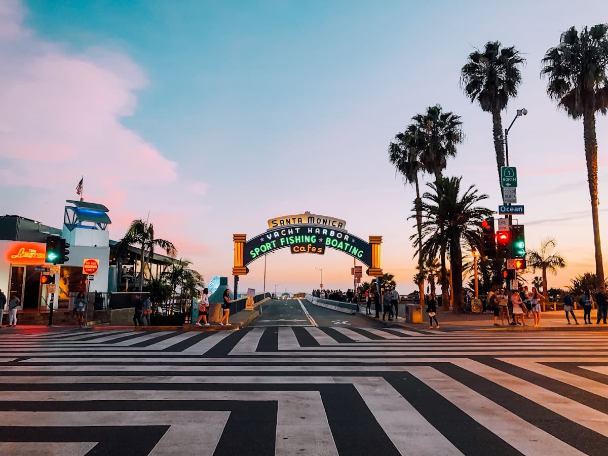 The iconic Santa Monica Pier entrance arch sign under a bright blue sky